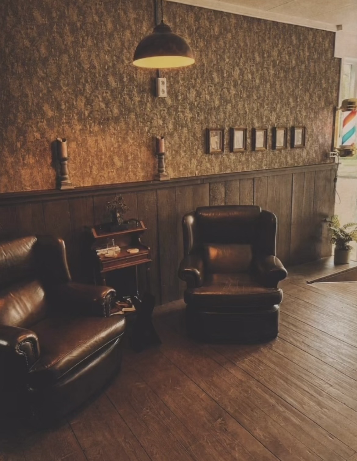 De wachthoek: twee leren fauteuils voor een lambrisering met lijstjes aan de muur